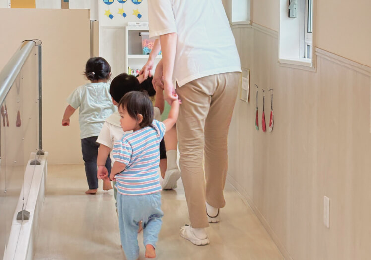 保育士と手をつないで歩く子どもたち