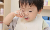 スプーンで給食を食べる園児