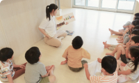 保育士が絵本の読み聞かせをしている様子
